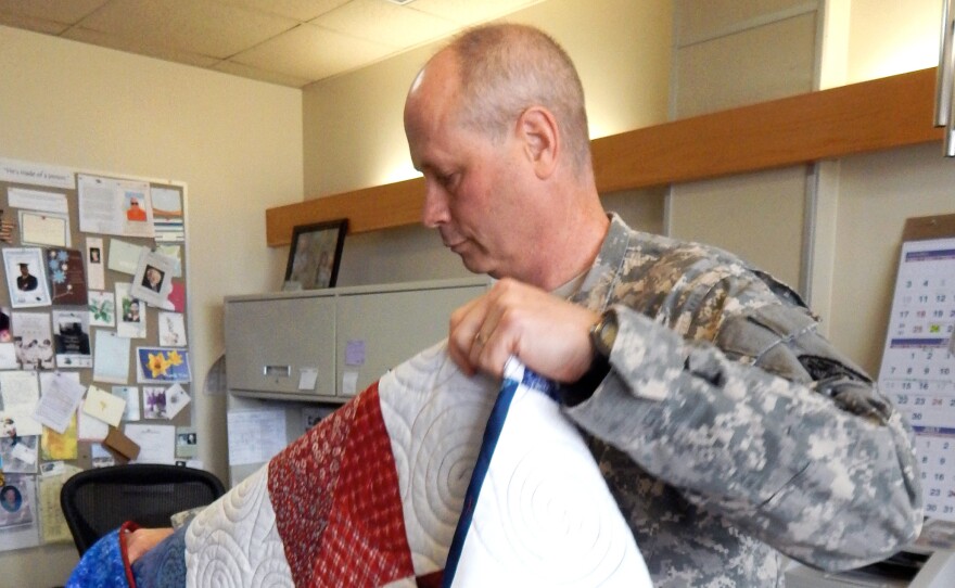 Col. Kenneth Trzepkowski, chief of palliative care at Madigan Army Medical Center, unfolds one of the handmade quilts donated to the hospital for the palliative care patients.
