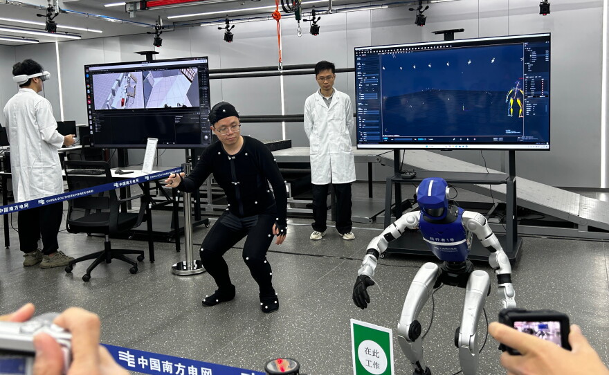 Humanoid robots getting training from a human staffer at China Southern Power Grid company in Guangzhou city. Sectors not traditionally in high tech are also developing their own humanoids.
