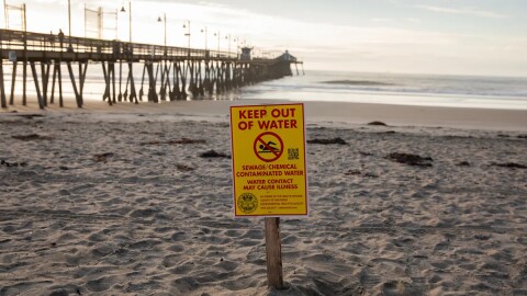 A warning sign about sewage and chemical contamination is posted along the shore of Imperial Beach on Nov. 21, 2025.
