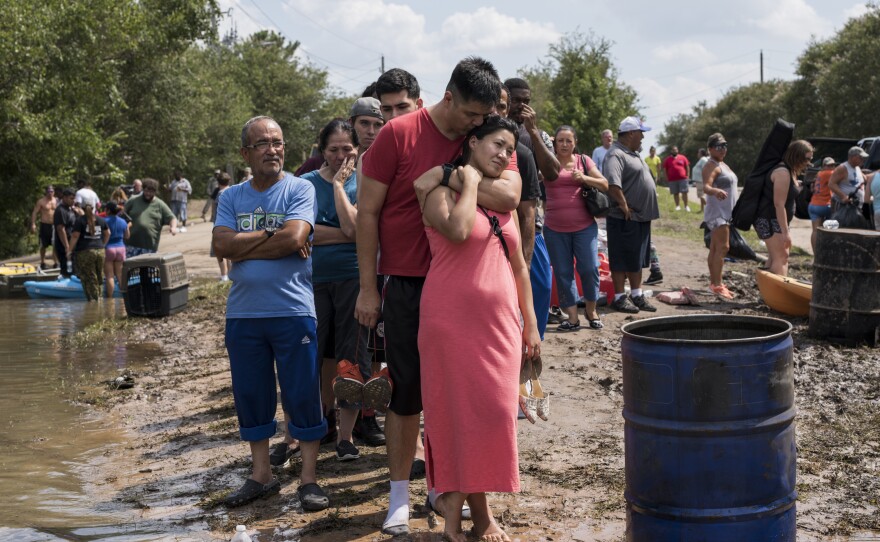 Ellie Nizamutdinova is comforted by her partner, Arnulfo Moreno, while they wait in line for a boat ride to check on their flooded home along Barker Cypress road on the west side of Houston.