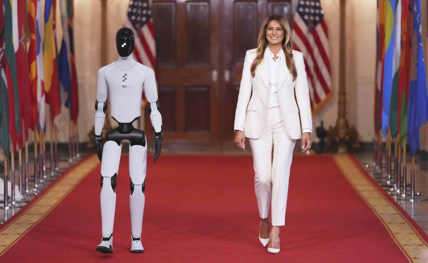 First lady Melania Trump arrives, accompanied by a robot, to attend the "Fostering the Future Together Global Coalition Summit," with other first spouses, at the White House, Wednesday, March 25, 2026, in Washington.