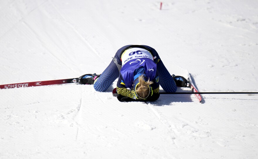 Ukraine's Oleksandra Kononova collapses after crossing the finish line and earning silver in the women's biathlon middle distance standing event on Tuesday.