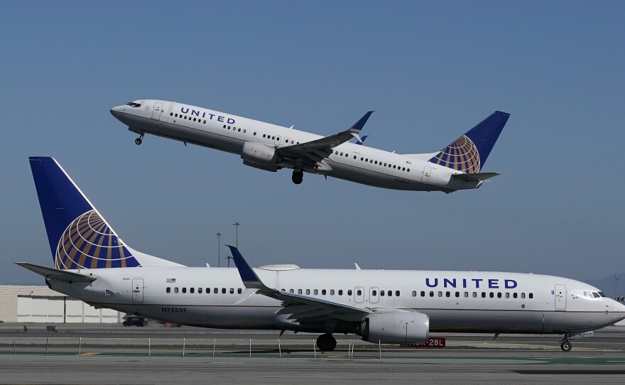 A United Airlines airplane takes off over a plane on the runway at San Francisco International Airport. The company is offering vaccinated customers the chance to win free flights for a year.