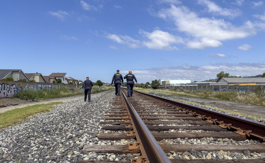 Police walk down a train line at the scene of cut AT&T wires.