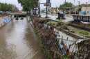 A metal fence covered in debris falls into a flooded stormwater channel in San Diego, Jan. 22, 2024.