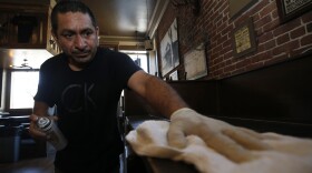 Miguel Colio cleans tables at the Goldfield Trading Post restaurant in Sacramento, Calif., Wednesday May 20, 2020.