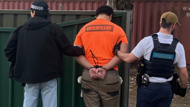 In this photo provided by the Australian Federal Police, a man, center, is arrested by police in Londonderry in western Sydney, Friday, June 19, 2026.