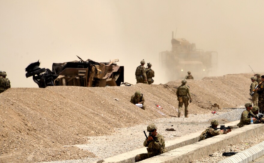 U.S. soldiers keep watch near the wreckage of their vehicle at the site of a Taliban suicide attack in Kandahar in August 2017.