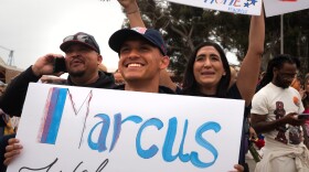 A family waits outside the Naval Air Station North Island dock holding a sign that says "Marcus welcome home" on Oct. 15, 2024.