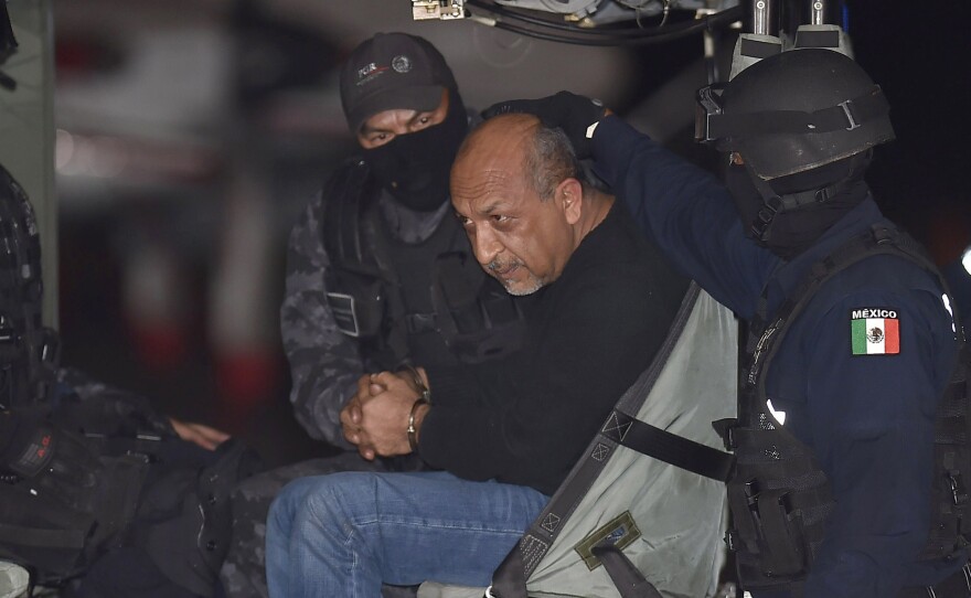 Mexican federal police escort Servando Gomez (center), aka "La Tuta," in a helicopter upon his arrival at the airport in Mexico City on Feb. 27. The most-wanted drug lord presided over the Knights Templar cartel in western Michoacan state.