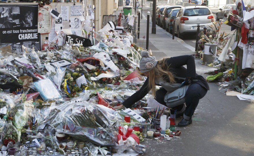 A woman looks at flowers placed near the headquarters of the magazine Charlie Hebdo in Paris, on Feb. 7. Islamist extremists stormed the offices of the satirical newspaper,  killing 12 people in January.