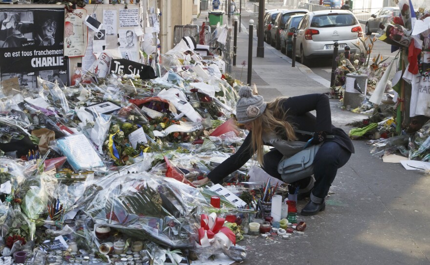 A woman looks at flowers placed near the headquarters of the magazine Charlie Hebdo in Paris, on Feb. 7. Islamist extremists stormed the offices of the satirical newspaper,Â  killing 12 people in January.