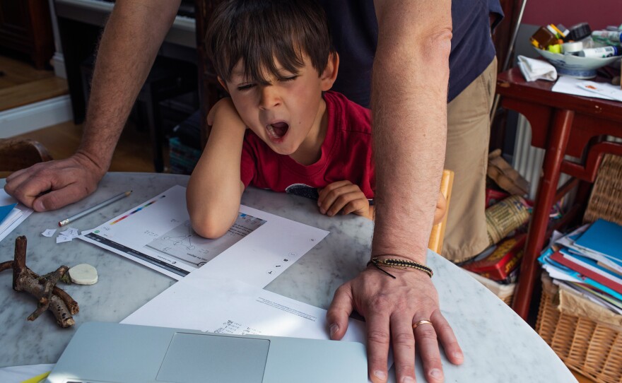 Joe yawns while working on a math problem with his father.