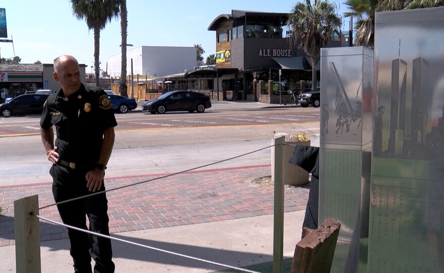 A firefighter stands near a memorial depicting the World Trade Center towers with a piece of steel from the actual towers in the middle, outside Fire Station 21 in Pacific Beach on September 2, 2021.