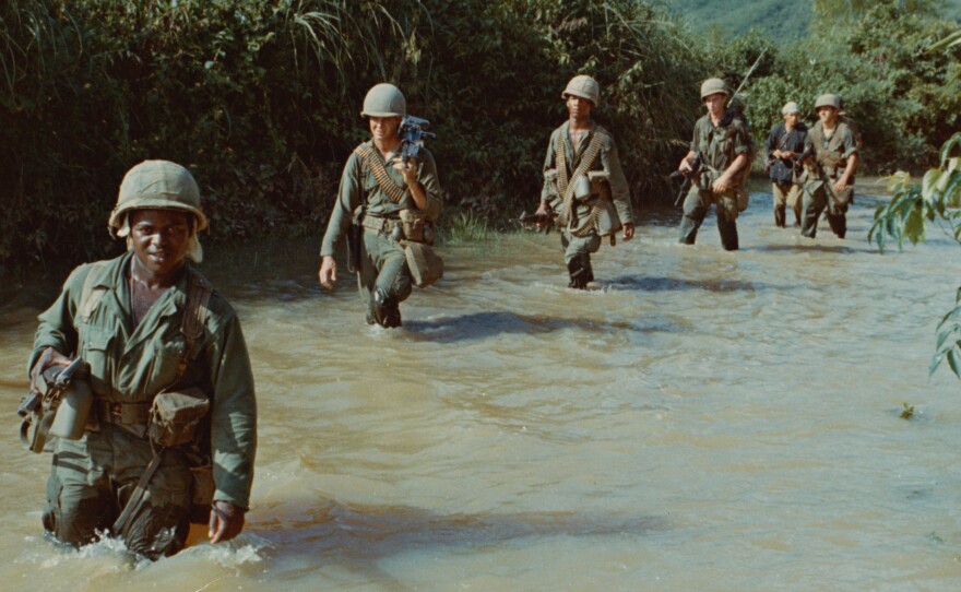 American soldiers advance through a rice paddy during the Vietnam War.