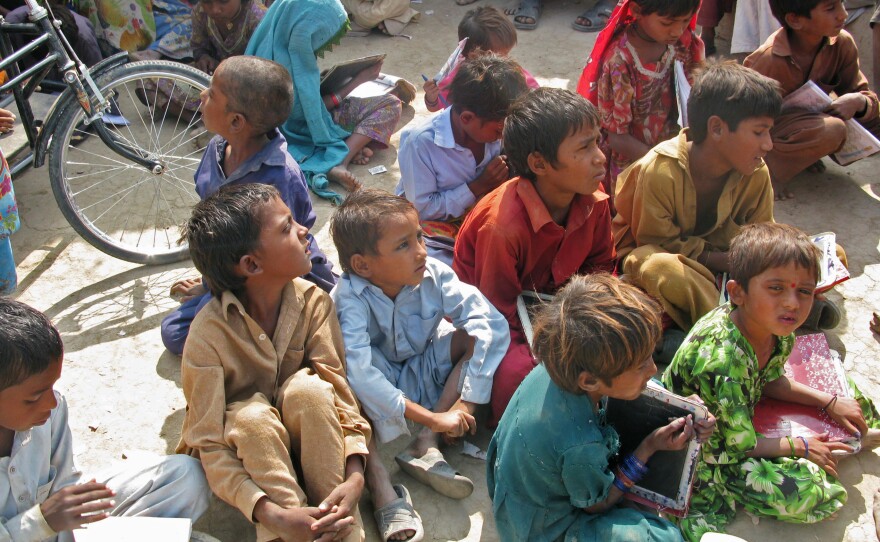 So many children gather at the cowshed for instruction that they spill outside.