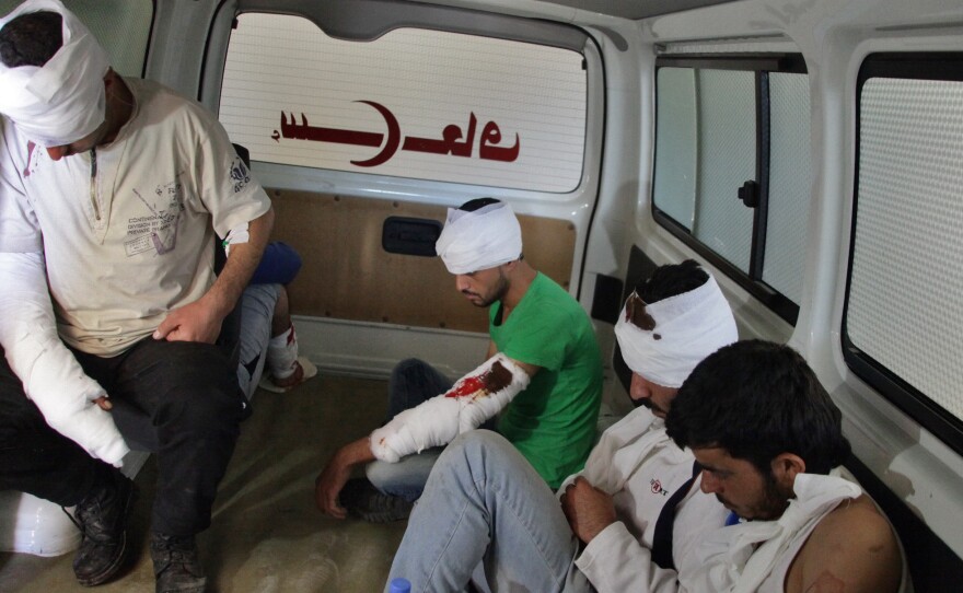Wounded rebel fighters sit in the back of an ambulance in Aleppo on Thursday. The Syrian government and its Russian allies declared a pause in the fighting and urged rebels to leave the eastern part of the city, but clashes broke out Thursday.