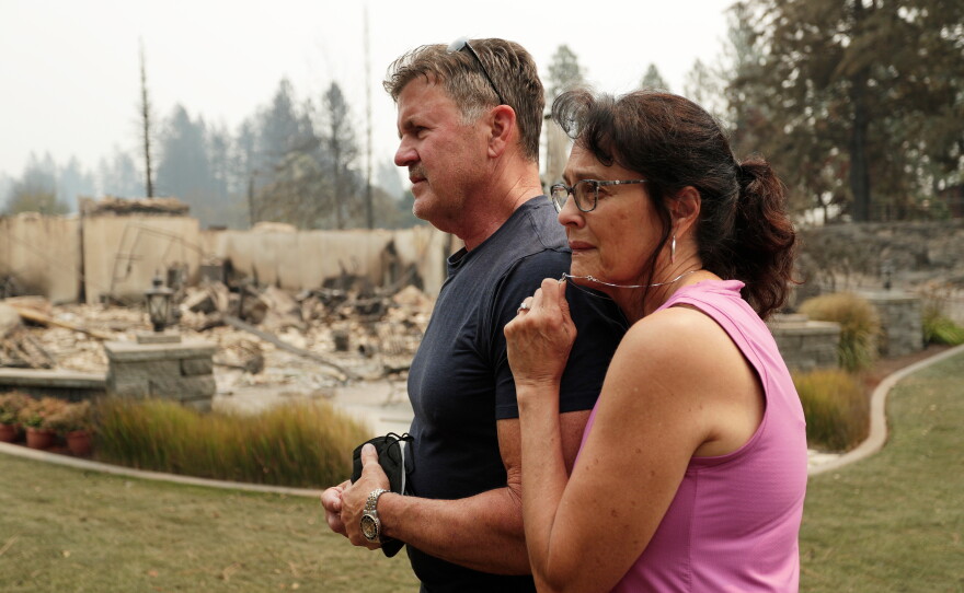 Dan Munson and his wife Suzi Munson stand in the backyard of their house on W. TIffany Ave. which burned in a wildfire, on Aug. 2, 2026, in Spokane, Wash.