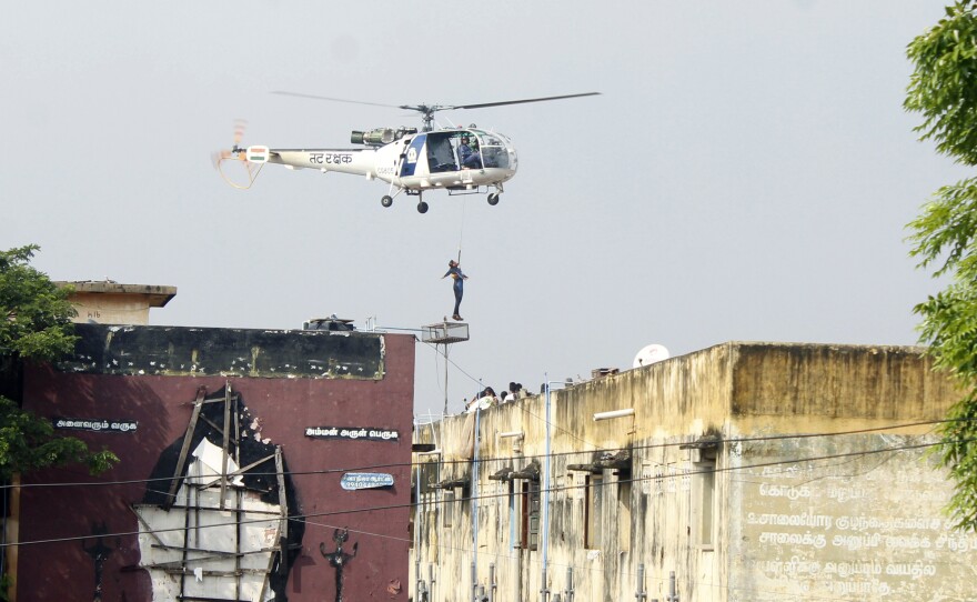 An Indian rescue helicopter lifts a man off an apartment roof on Friday.