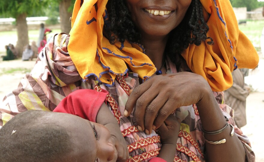 A mother and child at Muna informal displaced people's settlement. They're among 13,000 people at the camp, far from home after fleeing Boko Haram violence. They're calling for more Nigerian government and relief aid amid a malnutrition emergency and the lean pre-harvest farming season.