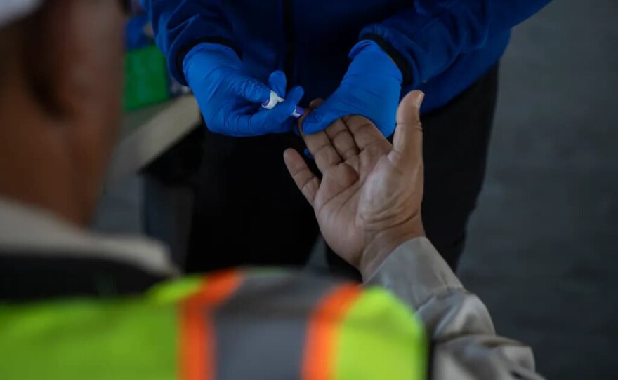 UCSF-Fresno staff member checks the blood sugar of a farmworker during a check-up in an equipment barn during a Rural Mobile Health program visit at a farm outside of Helm on June 16, 2025.