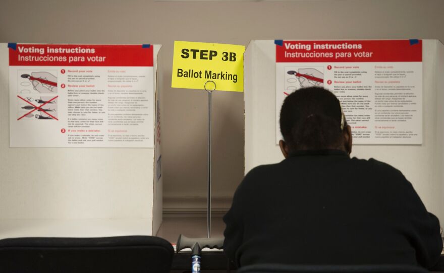 A voter casts a ballot at an absentee voting station in Fairfax, Va. Many polling places are preparing for the possibility of violence on Election Day.
