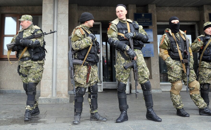 Armed men in military fatigues stood guard Monday outside a regional administration building they seized in the eastern Ukrainian city of Slovyansk.