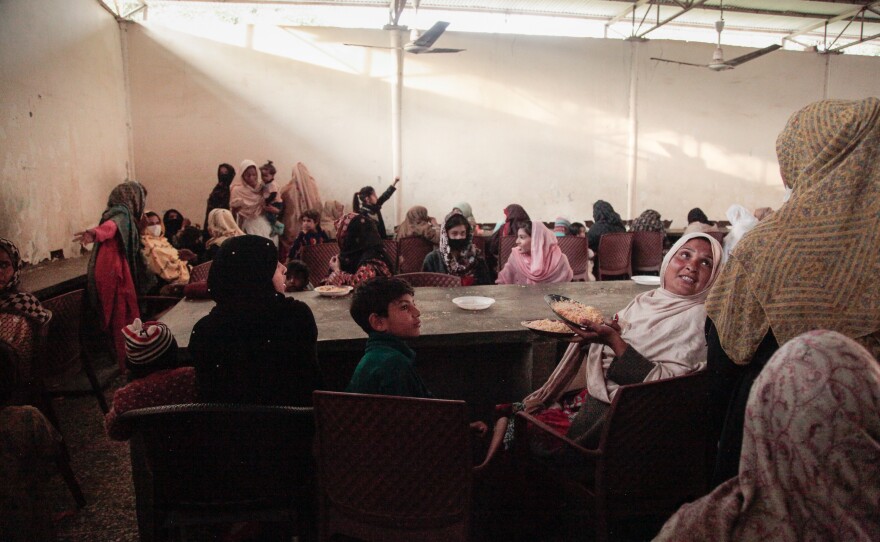 Women sit in a gender-segregated hall, waiting to be served free food cooked in open-air stalls surrounding the shrine to the Sufi saint Bari Imam. Men and women hoping for the saint's blessings pay cooks to prepare the food for hungry shrine visitors.