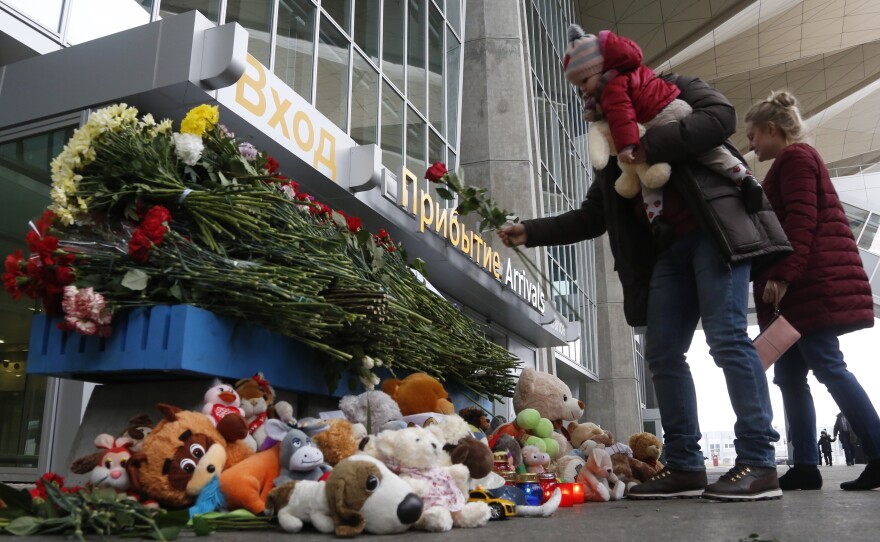 A family leaves flowers and toys at an entrance of Pulkovo airport outside St. Petersburg, Russia, during a day of national mourning for the plane crash victims.