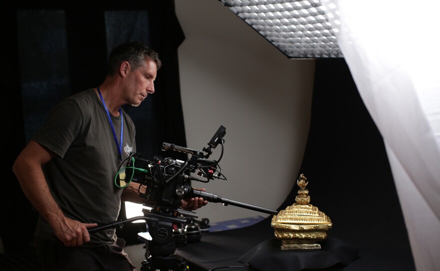 A camera operator films the gold box artifact.