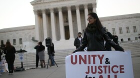 A women holds a sign that reads 'Unity & Justice for All' during a protest in front of the U.S. Supreme Court, on April 25, 2012 in Washington, DC.