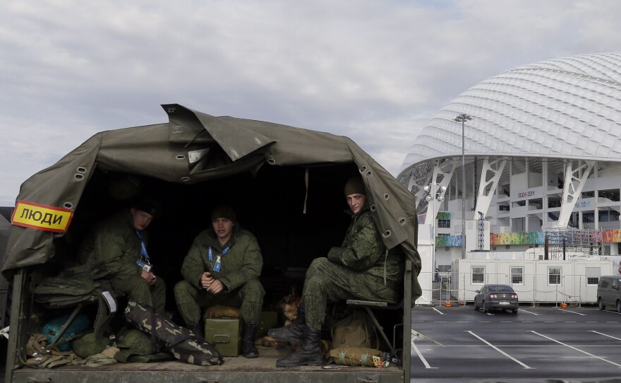 Security personnel sit in the back of a truck outside the Fisht Olympic Stadium in Sochi. Security concerns are one reason why many U.S. fans and family are not going to this year's games.