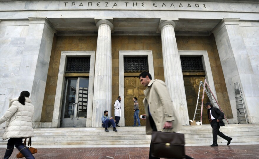 People walk past the Bank of Greece headquarters in Athens.
