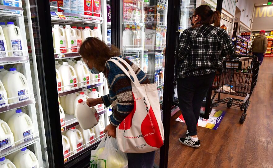 A person pulls out a gallon of milk as people shop at a grocery store in Monterey Park, Calif, on April 12. Prices for groceries and other consumer goods have continued to surge.