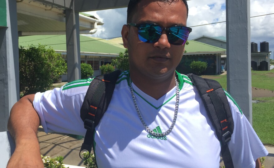 Govin Munswami stands outside the University of Guyana Berbice in Region 6. Both his wife and his mother died by suicide. On her deathbed, his wife made him promise to finish his degree in education.