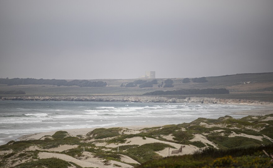 A building from the Vandenberg Space Force Center appears over a hill overlooking Surf Beach in northern Santa Barbara County on July 20, 2023. Tthe Federal lease of wind turbines offshore would bring energy built up to the Vandenberg base. Photo by Larry Valenzuela, CalMatters/CatchLight Local