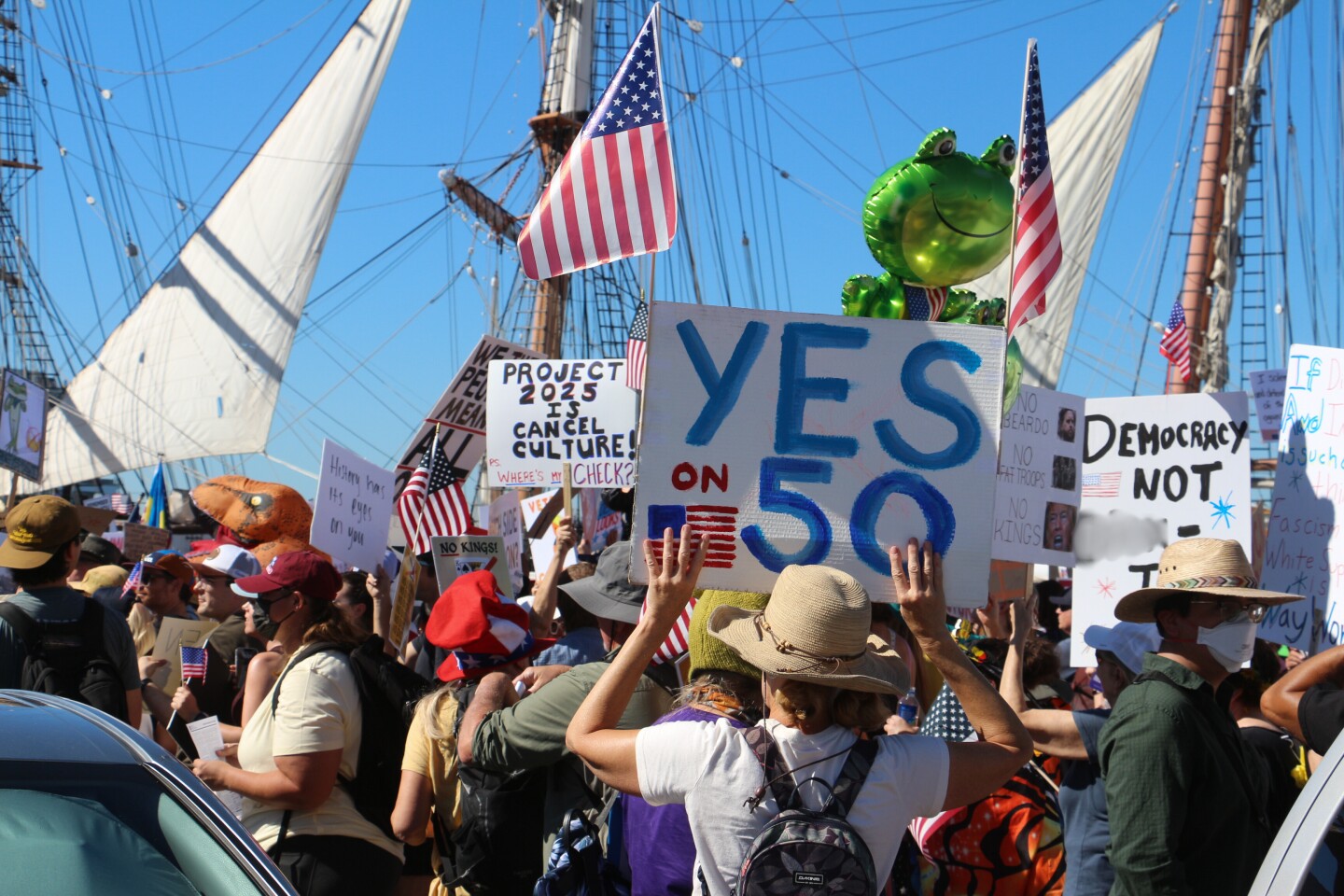 A crowd of protestors hold up signs as they march down Waterfront Park near downtown San Diego during a "No Kings" protest on Oct. 18, 2025.
