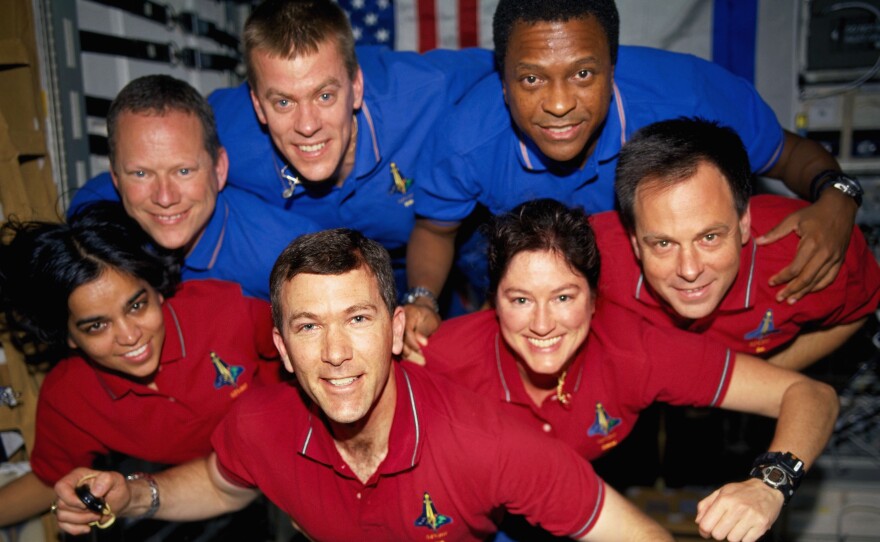 A portrait of the STS-107 crewmembers aboard the Space Shuttle Columbia in early 2003. From the left (bottom row), wearing red shirts to signify their shift's color, are Kalpana Chawla, Rick D. Husband, Laurel B. Clark, and Ilan Ramon. From the left (top row) are David M. Brown, William C. McCool and Michael P. Anderson.