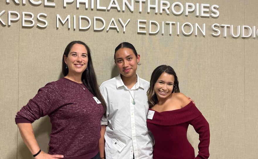 High Tech Middle Media Arts teacher Rebecca Carnahan (left) stands next to students Oryan Navarrete and Abby Dutra (right) in the KPBS Midday Edition studio, Sept. 22, 2025.