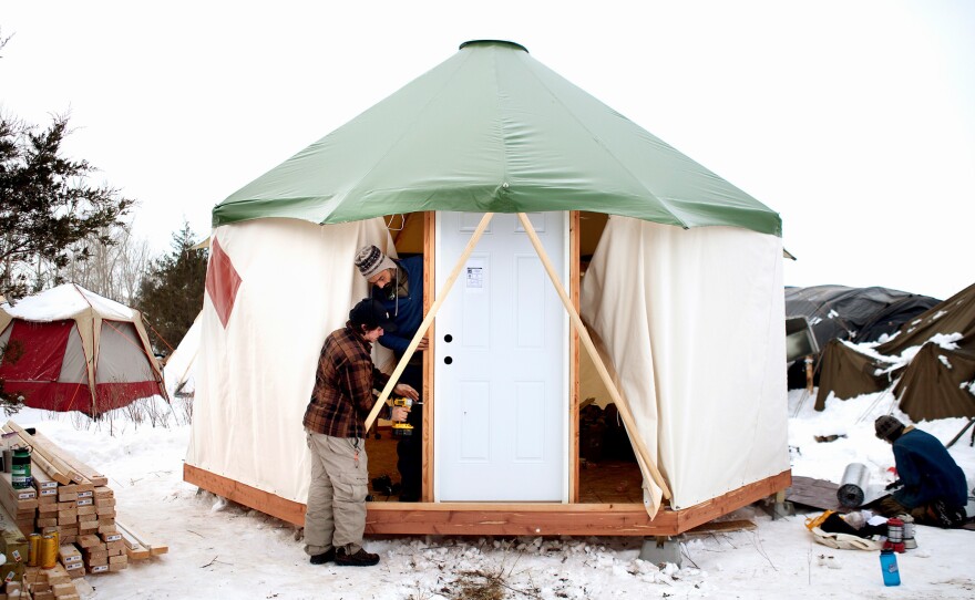 (Left) Flutter-By, a newer arrival, rests in the middle of his school bus, "Mamacita," which sleeps 12 people side-by-side. (Right) Brad Kallio of Michigan and Linus Yellowhorse of Arizona patch roofing on a dwelling at the Oceti Sakowin camp. (Bottom) Protestors from North Carolina brought a "yome," a combination yurt and dome, to erect and leave at the Rosebud camp for whoever needs it.