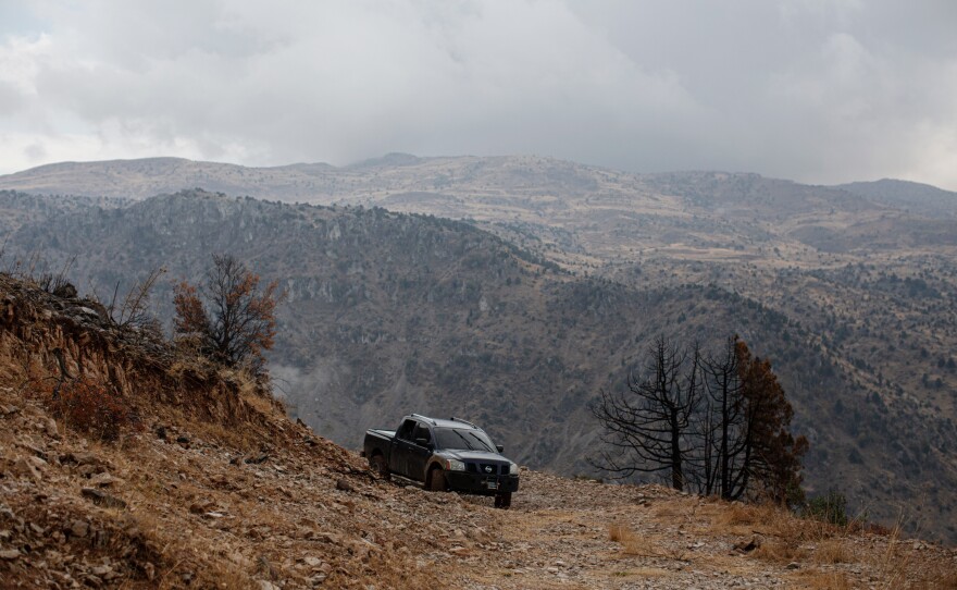 A pick-up truck that's been modified to be used for fighting wildfires is parked amid cedar and juniper trees that were burned in a recent wildfire, in the Mishmish forest.