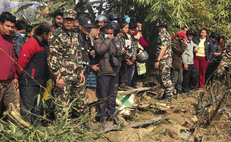 Locals watch the wreckage of a passenger plane in Pokhara, Nepal, Sunday, Jan.15, 2023. A passenger plane with 72 people on board has crashed near Pokhara International Airport in Nepal, the daily newspaper Kathmandu Post reports. The plane was carrying 68 passengers and four crew members.