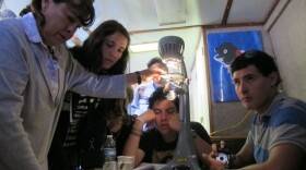 Patricia Moore examines water from San Diego Bay under a microscope with her students during a boat ride, July 26,2012.