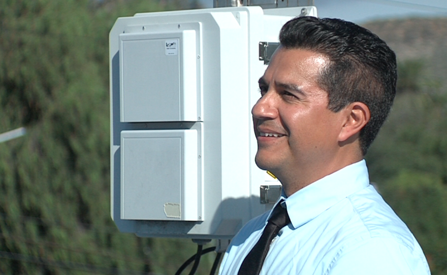 David Flores stands next an air pollution monitor in a San Ysidro neighborhood, Jan. 10, 2017.