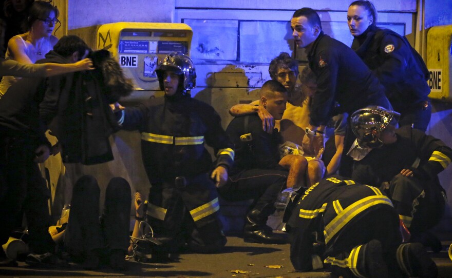 French fire brigade members aid an injured person near the Bataclan concert hall.
