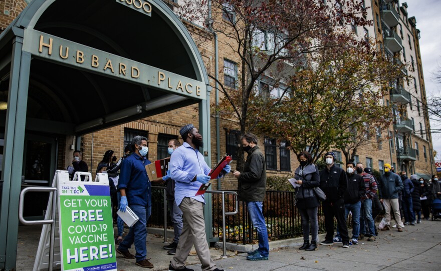 People line up outside a free COVID-19 vaccination site that opened Friday in Washington, D.C. The local health department is stepping up vaccination and booster shots as more cases of the omicron variant are being identified in the U.S.
