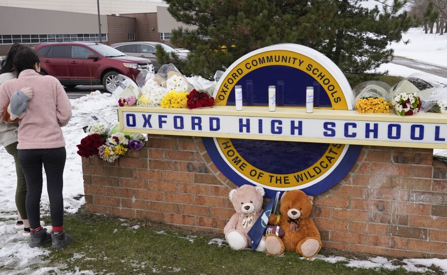 Students stand outside Oxford High School, near memorial items that were placed after the November 2021 shooting that took place at the Michigan school.