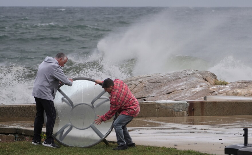 John Garrisi, left, and Gaige Graf move an outdoor table away from the shorefront during the early stages of a nor'easter storm on Friday.