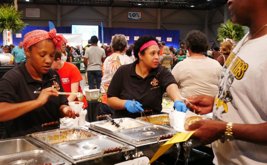 Restaurant workers dole out chicken fricassee at the "Taste of EatLafayette" festival in the sprawling Cajundome arena in Lafayette, Louisiana. Locals say Bourdain captured the subtleties of their culture and cuisine, even if at times some thought he overemphasized alcohol.