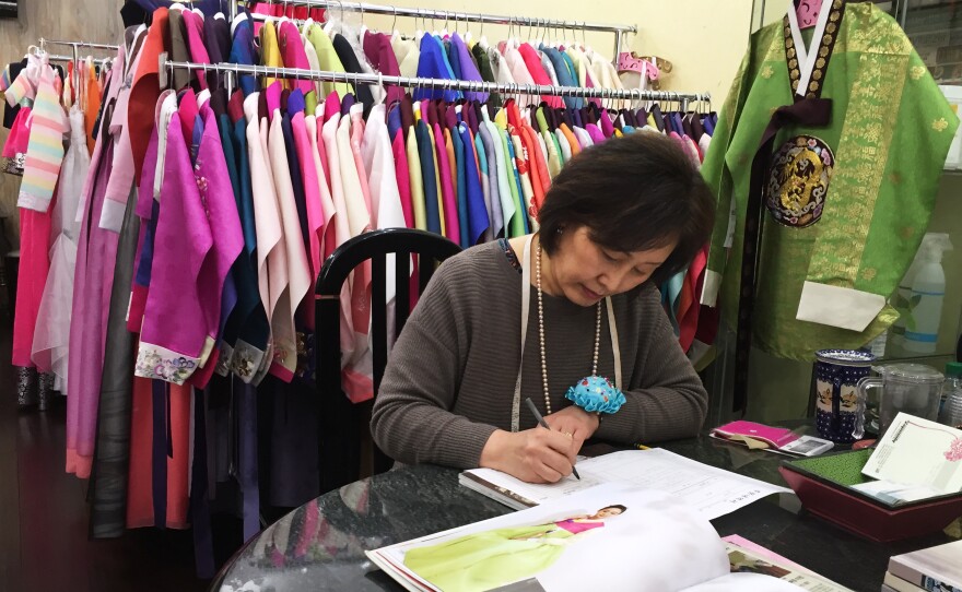 Youjung Jung takes a customer's order for a new outfit at her store Hanbok Story in Queens, N.Y.